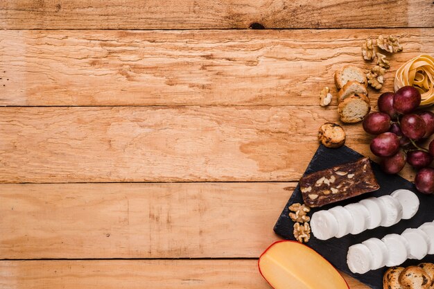 Vista elevada de ingredientes crudos saludables con queso en piedra de pizarra