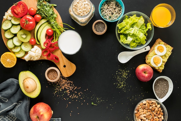 Vista elevada de los ingredientes; frutos secos y verduras sobre fondo negro