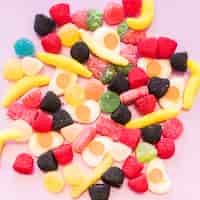Foto gratuita vista elevada de jalea colorida y caramelos de azúcar gomosos sobre fondo rosa
