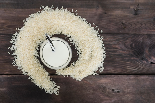 Vista elevada de la leche de arroz y granos de arroz dispuestos sobre fondo degradado