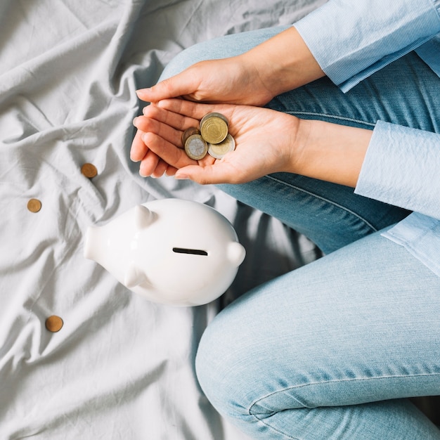 Foto gratuita vista elevada de la mano humana con monedas cerca de piggybank