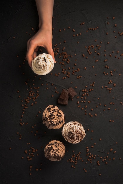 Foto gratuita vista elevada de una mano humana recogiendo muffin de chocolate