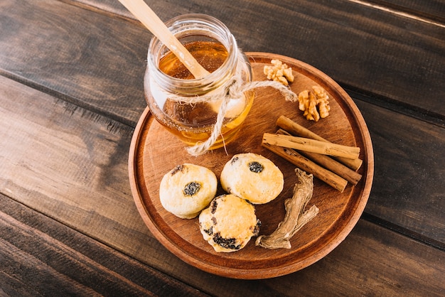 Vista elevada de la miel; nuez; canela; Tortas de taza y jengibre en tablero de madera