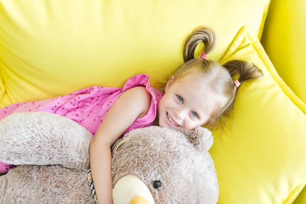 Vista elevada de una niña linda abrazando a su oso de peluche