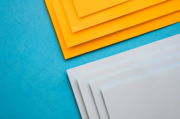 Vista elevada de papeles de cartón grises y amarillos sobre superficie azul