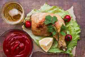 Foto gratuita vista elevada de pata de pollo a la parrilla adornada con salsa; cerveza y tomates cherry