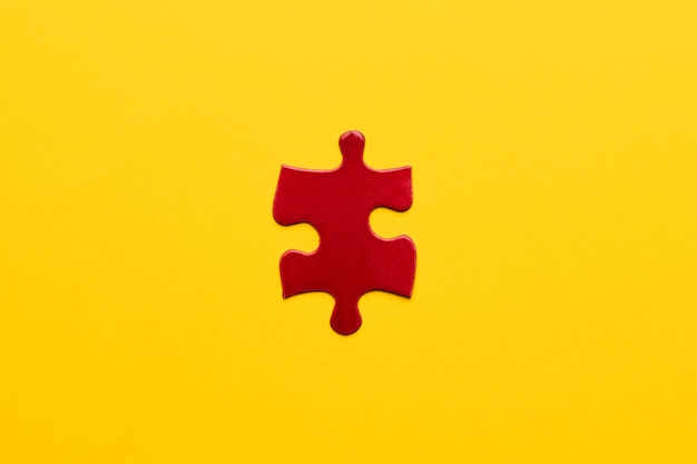 Vista elevada de pieza de rompecabezas rojo sobre fondo amarillo