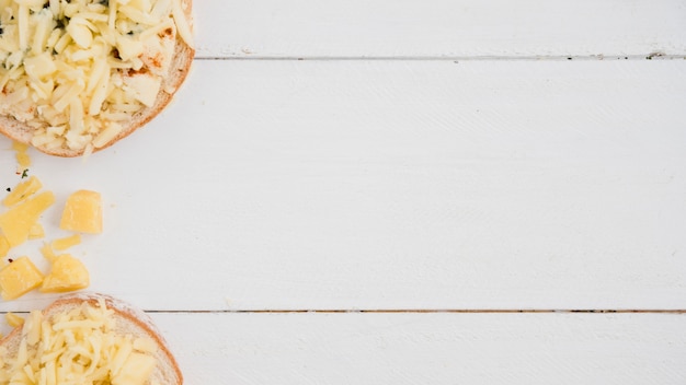 Una vista elevada de queso rallado en pan sobre la mesa blanca