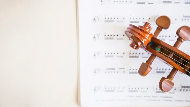 Vista elevada del rollo de violín de madera y cuerdas en notas musicales