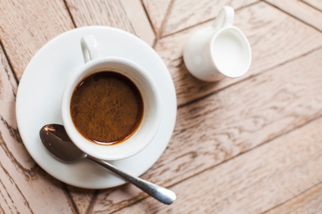 Vista elevada de sabrosa taza de café y jarra de leche de cerámica