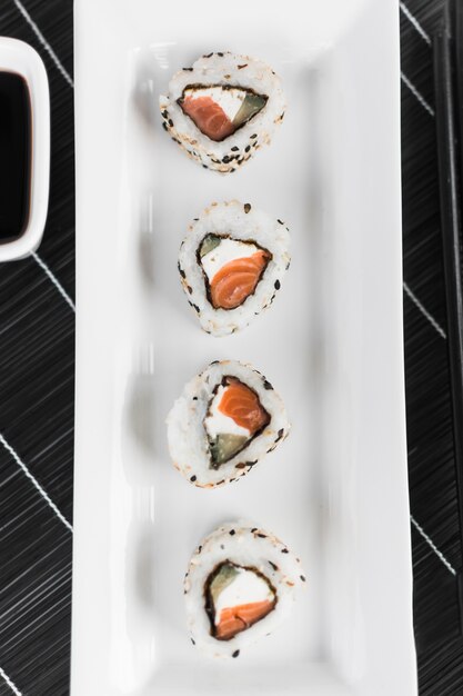 Vista elevada de sushi dispuesta en una bandeja blanca sobre la esterilla.