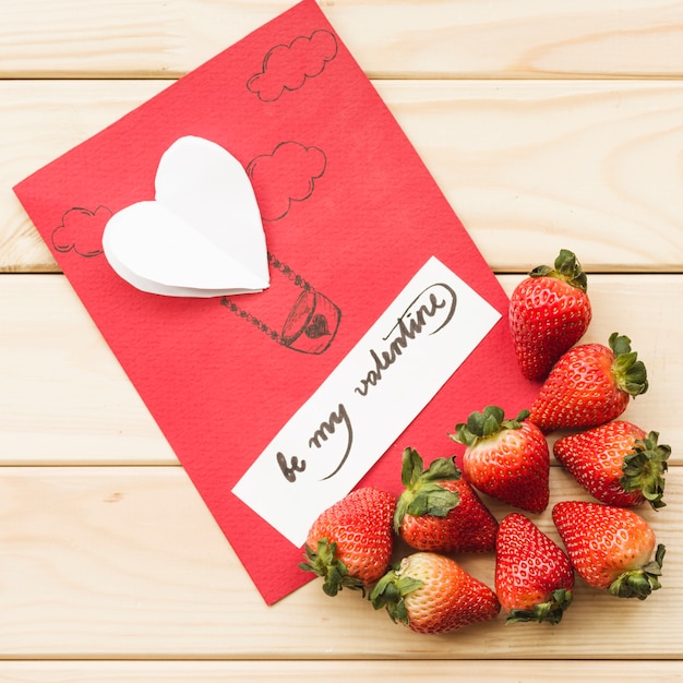 Vista elevada de la tarjeta del día de San Valentín con fresas sobre fondo de madera