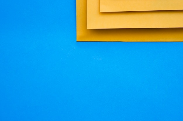 Vista elevada de tres craftpapers amarillos sobre fondo azul