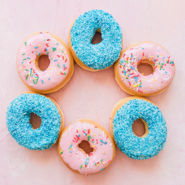 Vista elevada de varios deliciosos donuts sobre fondo rosa