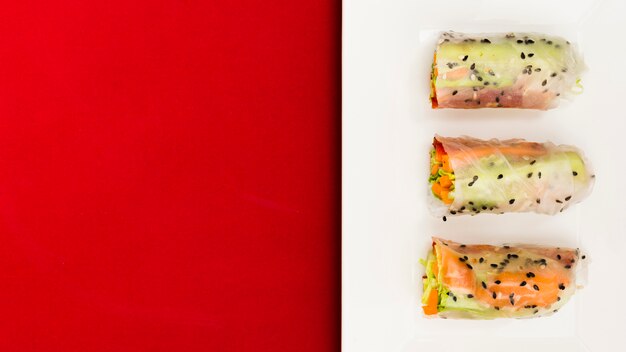 Una vista elevada de verduras frescas y salmón pescado rollitos de primavera en la placa