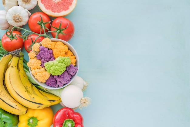 Vista elevada de verduras y frutas sobre fondo azul