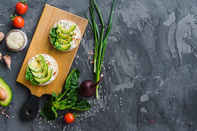 Vista elevada de verduras orgánicas con una sabrosa comida de pastel de arroz sobre un fondo de hormigón áspero gris