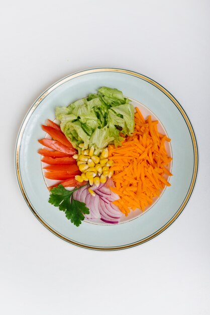 Vista elevada de zanahoria en rodajas; lechuga; tomate; maíz; cebolla y parley en la placa