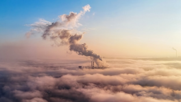 Vista de una estación termal en la distancia por encima de las nubes, columnas de humo, idea de ecología