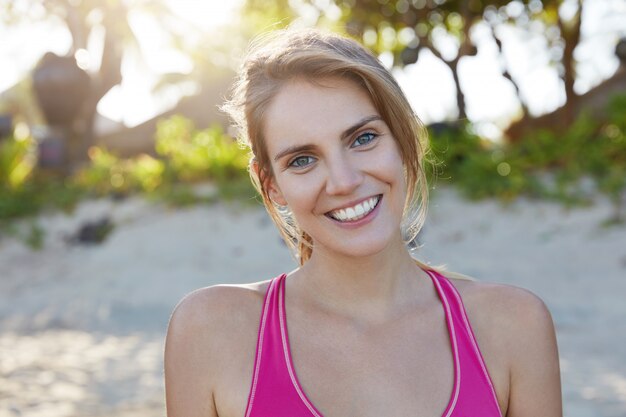 La vista exterior de la feliz y encantadora joven entrenadora de fitness se prepara para la clase magistral y participa en el entrenamiento activo, le gusta practicar deporte para una mejor vitalidad y flexibilidad. Estilo de vida activo