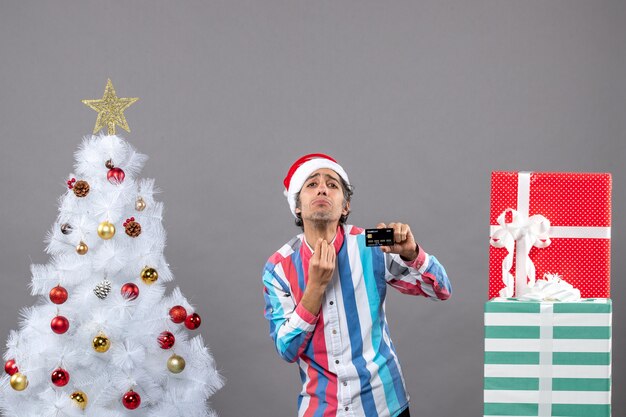 Vista frontal admira el hombre mostrando signo de beso de pie cerca del árbol de Navidad blanco
