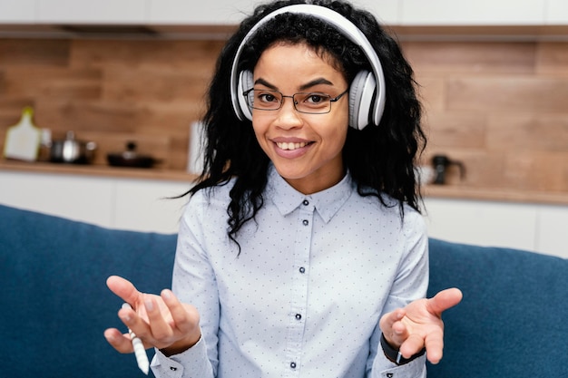 Vista frontal de la adolescente sonriente con auriculares durante la escuela en línea