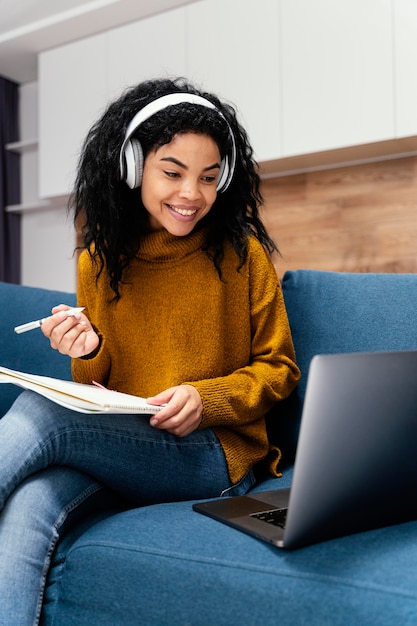 Vista frontal de la adolescente sonriente con auriculares durante la escuela en línea