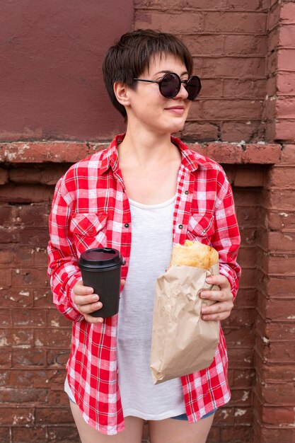 Vista frontal adolescente sosteniendo comida y café
