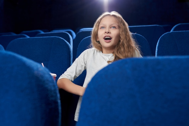 Vista frontal de una adolescente viendo una película de acción en el cine