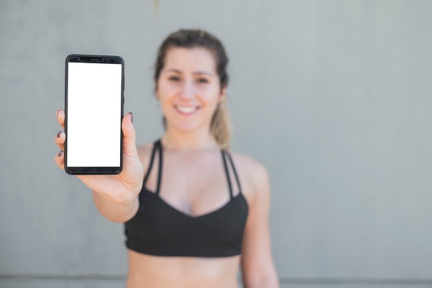 Vista frontal ajuste chica sosteniendo teléfono con maqueta