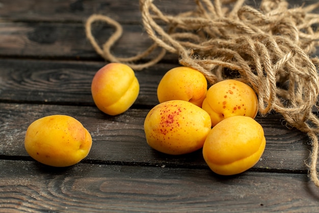 Vista frontal de albaricoques amarillos frutas frescas y suaves en el fondo rústico marrón fruta vitamina verano
