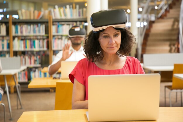 Vista frontal de la alegre mujer caucásica ajuste auriculares VR