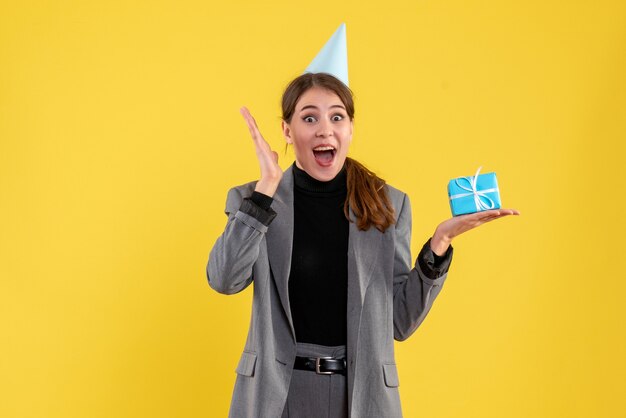 Vista frontal alegre niña con gorro de fiesta sosteniendo su regalo