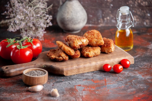 Vista frontal de alitas de pollo en tabla de cortar con tomates frescos fondo oscuro hamburguesa comida cena comida sándwich almuerzo ensalada horizontal