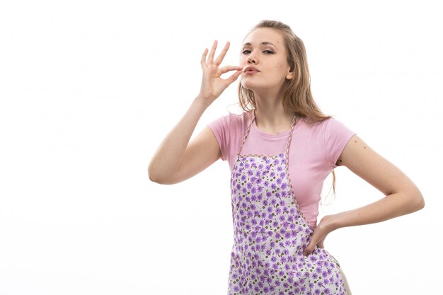 Una vista frontal ama de casa hermosa joven en camisa rosa capa colorida que muestra un signo delicioso