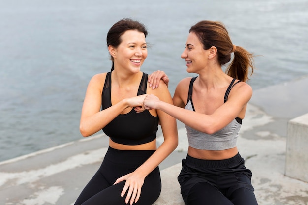 Vista frontal de amigas divirtiéndose mientras hacen ejercicio juntos al aire libre