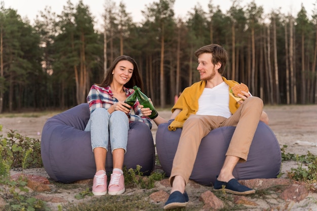 Vista frontal de amigos al aire libre con cervezas en pufs