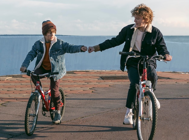 Vista frontal de los amigos del niño al aire libre en bicicletas