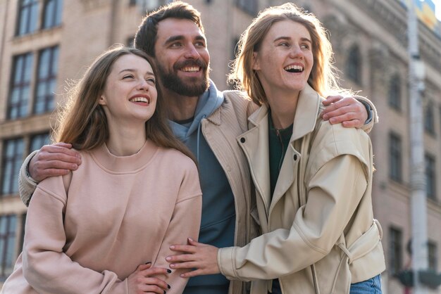 Vista frontal de amigos sonrientes al aire libre en la ciudad juntos divirtiéndose