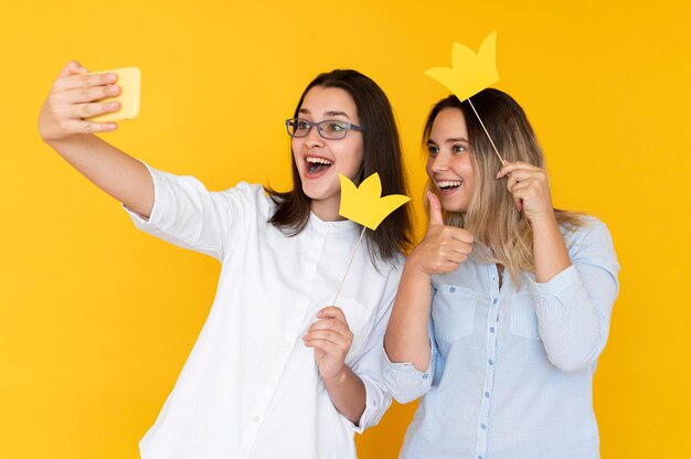 Vista frontal de amigos tomando selfies con corona