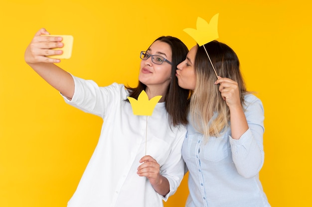 Vista frontal de amigos tomando selfies con corona