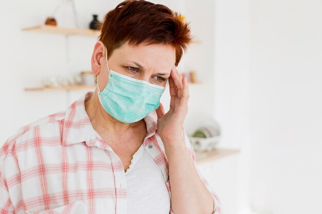 Vista frontal de la anciana con máscara médica no se siente bien