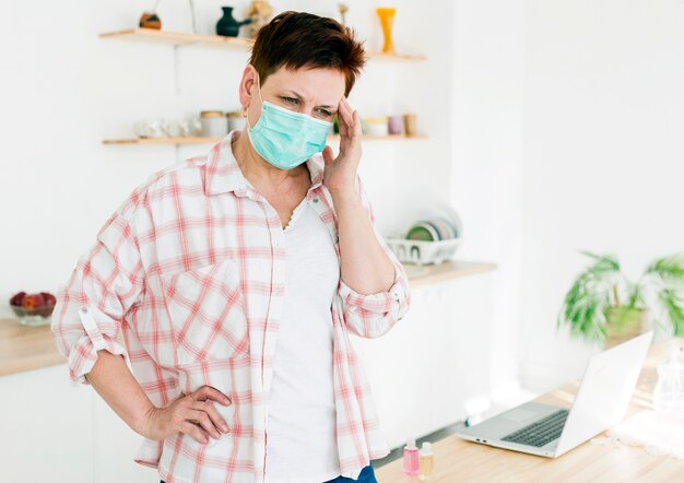 Vista frontal de la anciana con máscara médica y no se siente bien