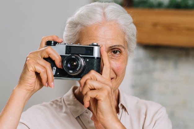 Vista frontal de una anciana tomando una fotografía de la cámara