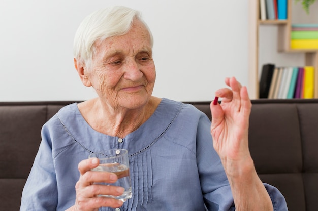 Vista frontal de la anciana tomando su píldora diaria