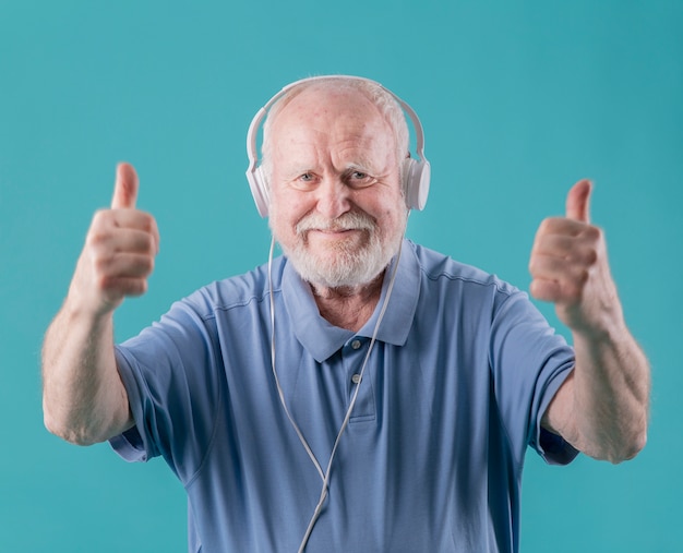 Vista frontal anciano con auriculares mostrando signo ok