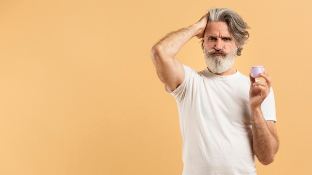 Vista frontal del anciano barbudo sosteniendo gel para el cabello con espacio de copia