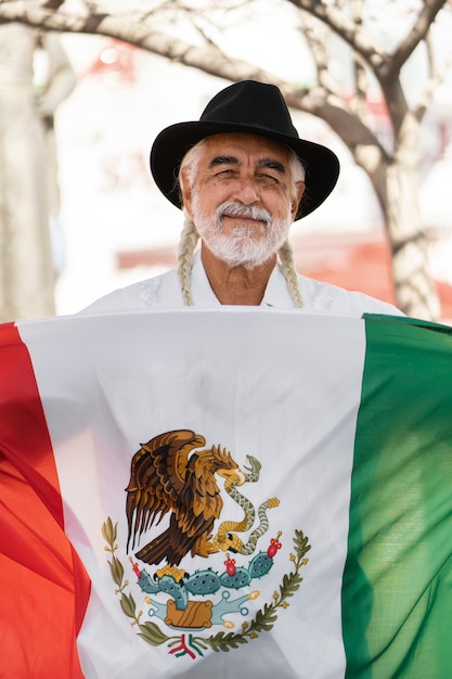 Vista frontal anciano sonriente con bandera mexicana