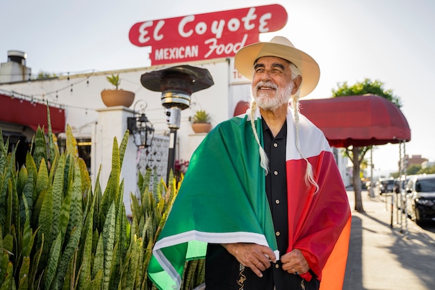 Vista frontal anciano sonriente con bandera mexicana