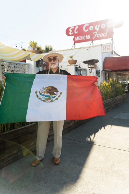 Vista frontal anciano sosteniendo bandera mexicana